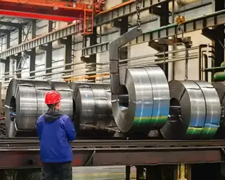 worker operating crane lifting hot rolled steel in factory